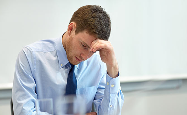 man in business attire looking down stressed