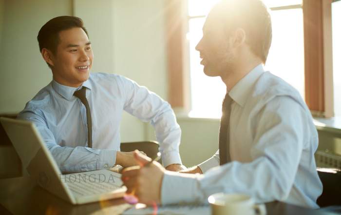 two businessmen talking in front of a laptop